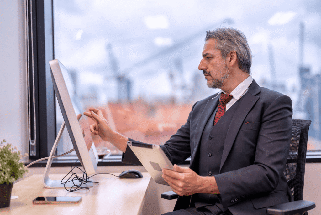 Man using a tablet and touch screen monitor, applying delegation strategies for project management