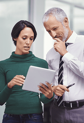 A man and a woman looking at a tablet.