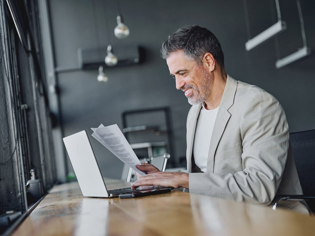 business owner reviewing sop documents before relaying them to his team via his laptop