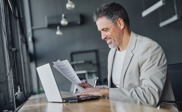 business owner reviewing sop documents before relaying them to his team via his laptop