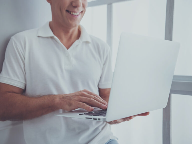 A small business owner happily working via his laptop, showcasing the benefits of workflow automation
