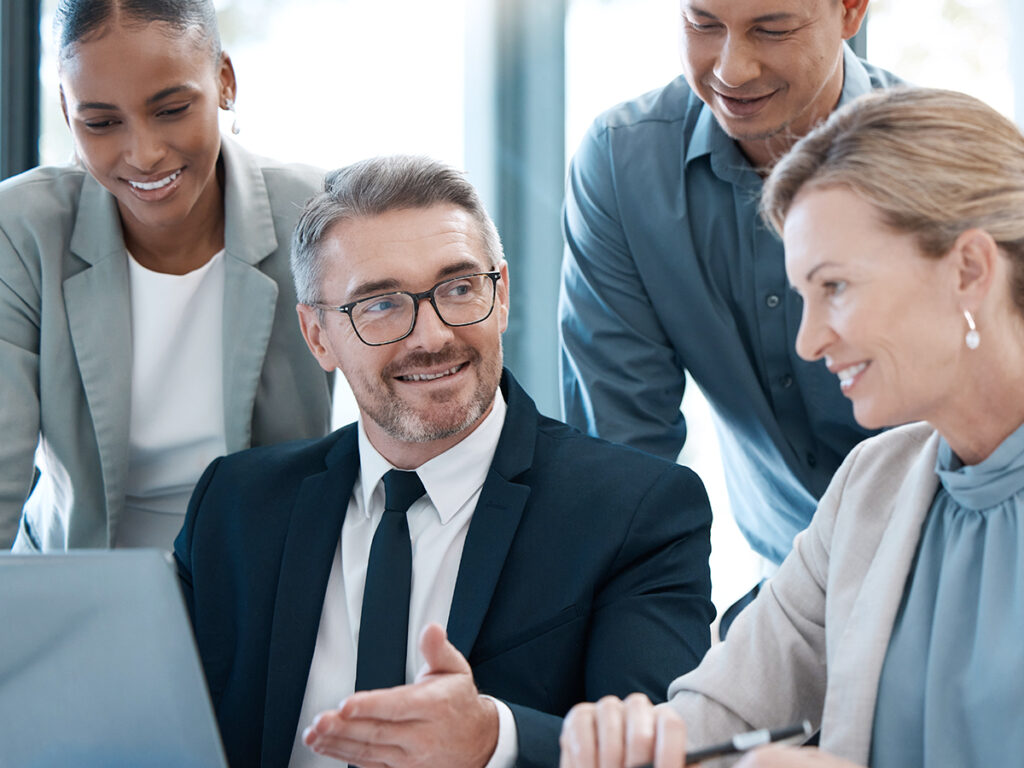 A small business team working on project management structure while discussing in front of a computer screen