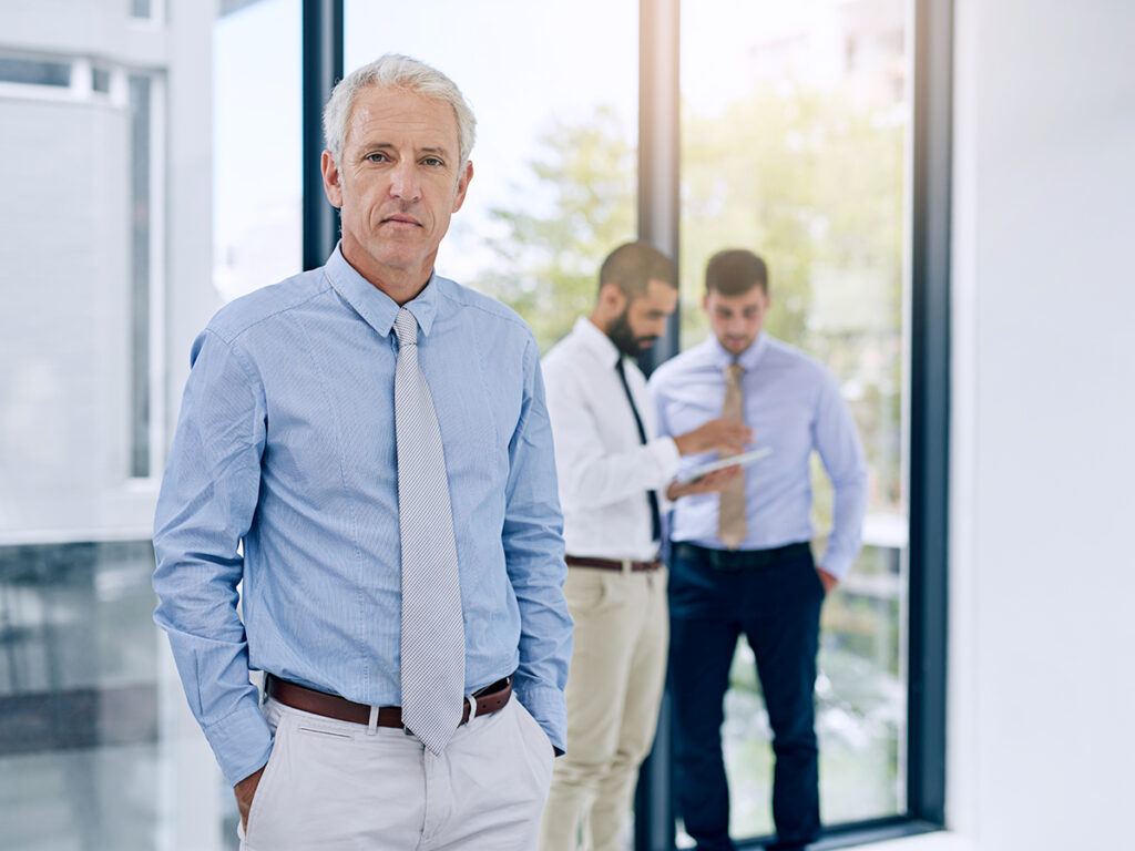 small business owner pauses while discussing business process improvements with employees