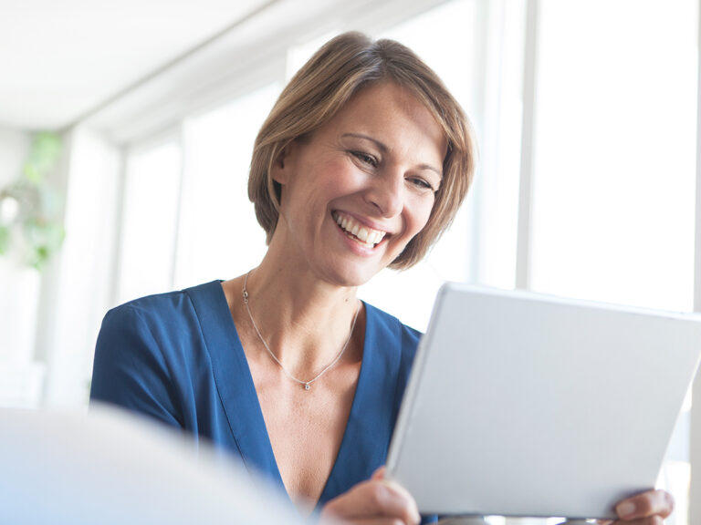 employee smiling while working on a laptop in the office with business process automation improving workflow efficiency