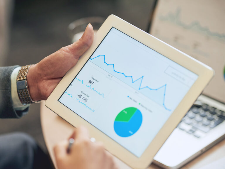 Business owner checks analytics on a tablet, showing how fear of delegation keeps leaders stuck reviewing every metric.