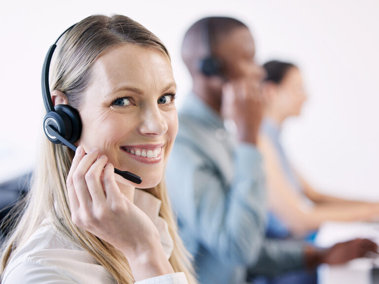 Happy call center agent with her team, showing how smart operations fixes play a key role in reducing employee turnover.