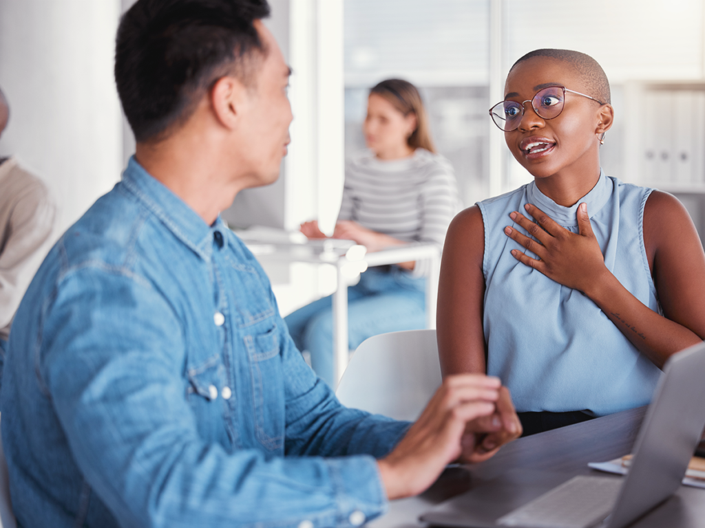 Two employees discussing work to address communication mistakes in teams.